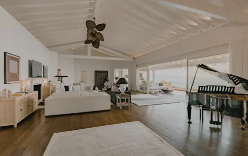 Spacious living room with high ceilings, elegant decor, and panoramic sea views through floor-to-ceiling windows.