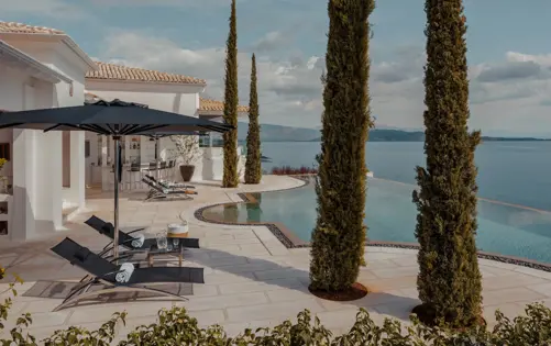 Seaside villa with an infinity pool, sun loungers, and serene views of the open sea.
