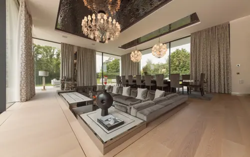 Sophisticated modern living and dining room with a sunken lounge, designer chandeliers, floor-to-ceiling windows, and elegant neutral tones.