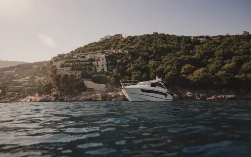 Seaside villa surrounded by lush greenery with a yacht anchored along the private coastline.