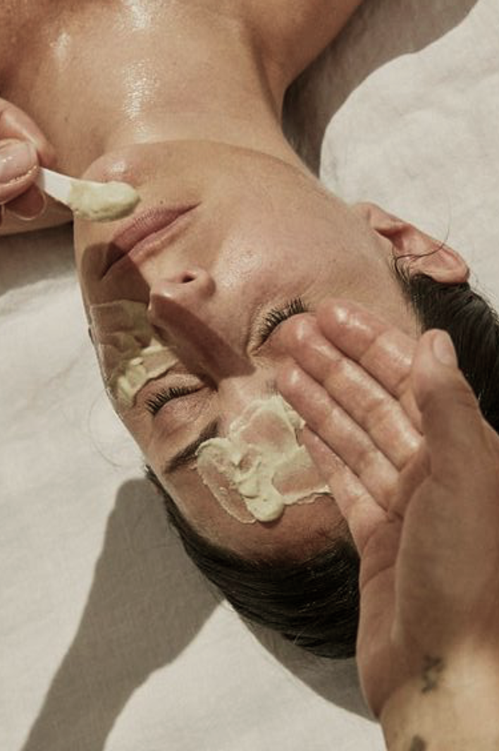 Close-up of a relaxing facial treatment with a skincare specialist applying a creamy mask to a woman’s face.