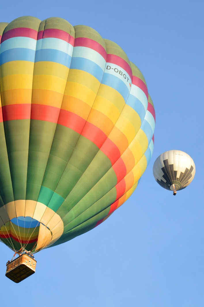 Colorful hot air balloons float gracefully against a clear blue sky, offering a serene aerial experience.