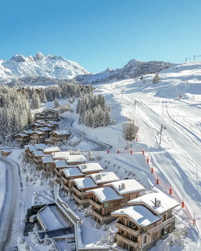 Luxurious mountain chalets nestled in a pristine snowy landscape, offering direct ski-in access and breathtaking alpine views.