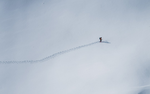 Solo skier making fresh tracks across untouched snow on a mountain slope.